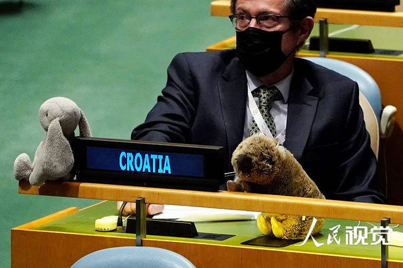 There are plush toys on the tables of representatives from various countries